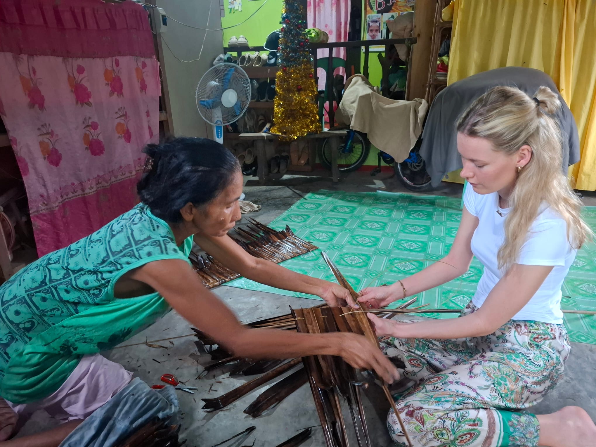 Young female traveller does weaving with a local villager in Philippines
