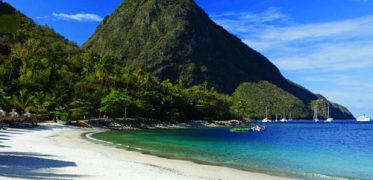 White sand tropical beach with turquoise waters and lush green mountains