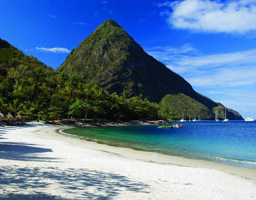 White sandy beach overlooking clear blue sea and lush mountains