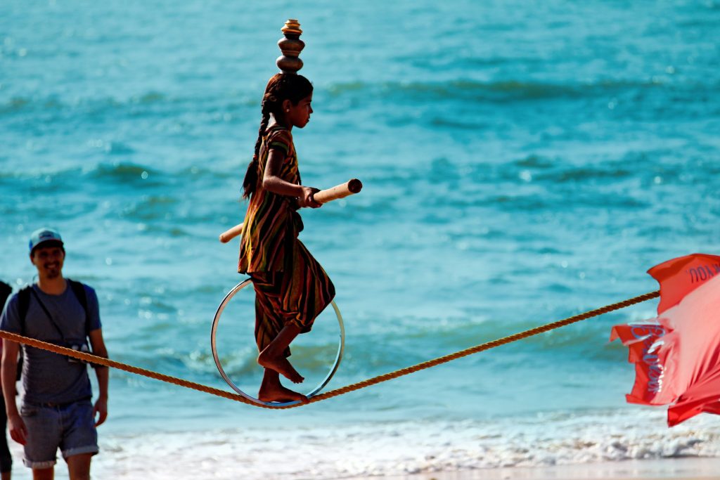 Young Indian walking on trapeze on a beach in India