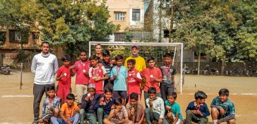 Volunteer coaches celebrating with a youth football team after a sports coaching session