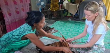 Young female traveller does weaving with a local villager in Philippines